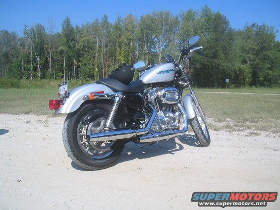Silver 2006 Victory Kingpin motorcycle parked on dirt road, rear 3/4 view
