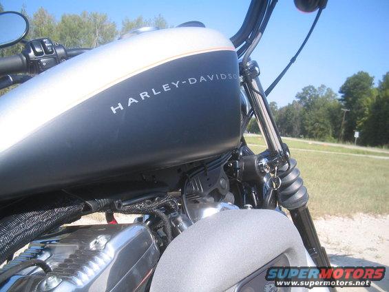 Motorcycle fuel tank with Harley-Davidson logo, chrome engine parts, and handlebars