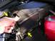 2007 Mazda 3 - Close-up of a hand interacting with a fuse box cover in a vehicle's engine bay.