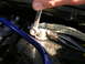 2007 Mazda 3 - A close-up shows a wrench being used to secure a car battery terminal, connecting a braided ground strap and electrical wires.