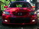 2007 Mazda 3 - Frontal view of a red 2007 Mazda 3, showing its grille, headlights, and fog lights.