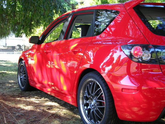 Red 2007 Mazda 3 hatchback, rear quarter view, parked outdoors under trees