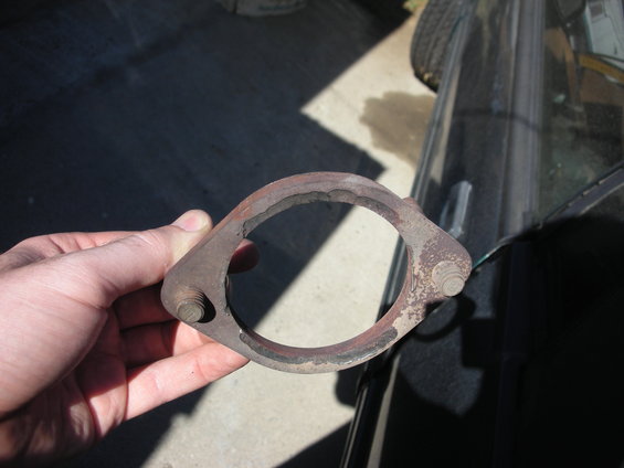 Hand holding rusty exhaust flange with two bolts