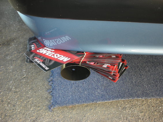 Stack of Mustang Boss 302 promotional cards tied with string, partially under a car's rear bumper