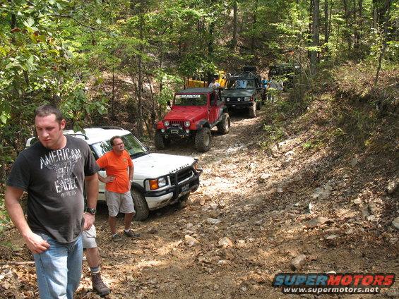 The party standing around waiting for the Rovers to climb a muddy little hill. 