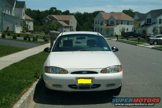 White 1999 Ford Escort parked curbside in front of houses