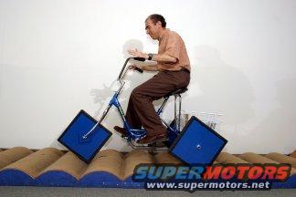 guy on a blue tricycle with square wheels going over bumps