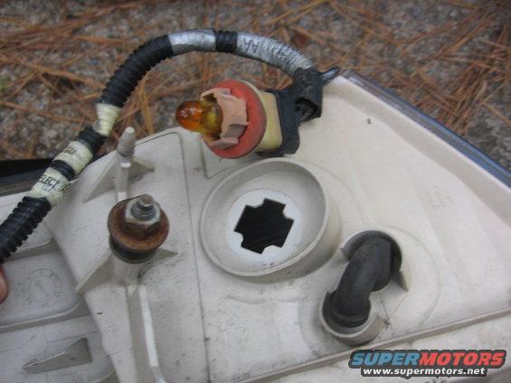 Tail light assembly with amber bulb, wiring harness, and mounting hardware. Supermotors.net logo visible