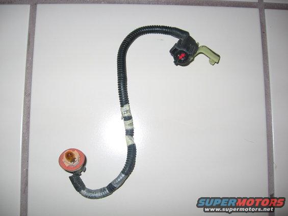 Wiring harness with a black corrugated tube, a black connector with a red insert, and a socket with a brown interior