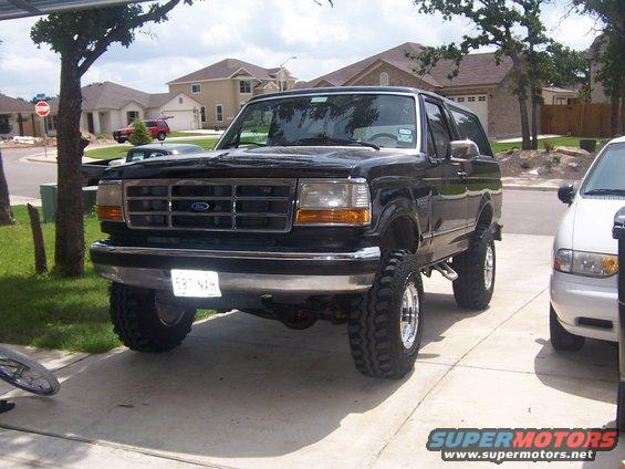 Black 1993 Ford Bronco with lifted suspension and chrome wheels parked in driveway