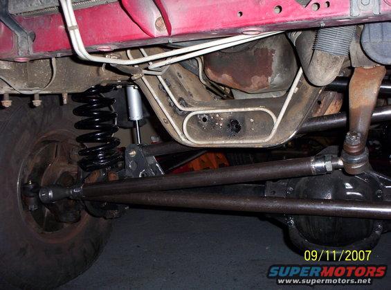 Undercarriage view of a vehicle's front suspension with a large coil spring and shock absorber
