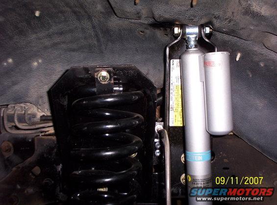 Black coil spring and silver Bilstein shock absorber assembly with yellow sticker