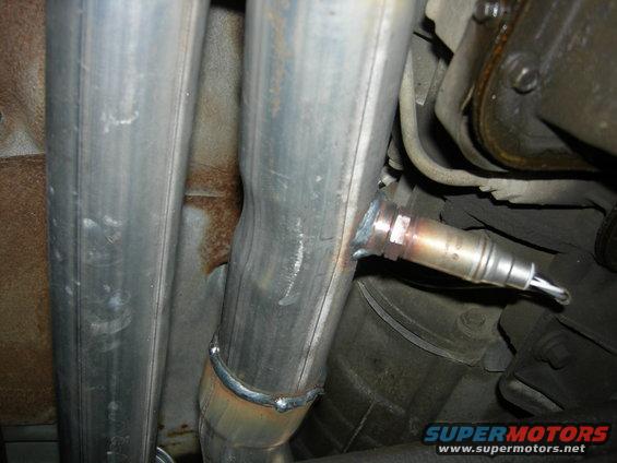 Exhaust pipe with welded joint and oxygen sensor attached. Underside view