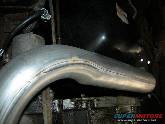 Exhaust pipe section above a greasy transmission housing