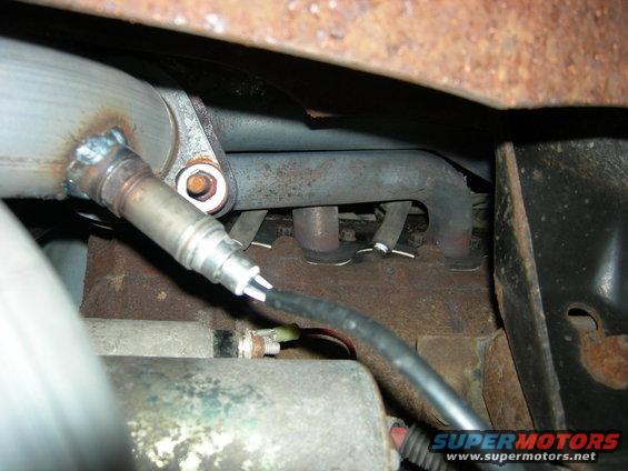 Exhaust manifold with oxygen sensor attached, showing rust and wear