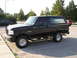 1993 Ford Bronco - A black Ford Bronco is parked in a lot, showing its side profile and aftermarket modifications.