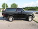 1993 Ford Bronco - This black SUV is parked near a body of water on a sunny day.