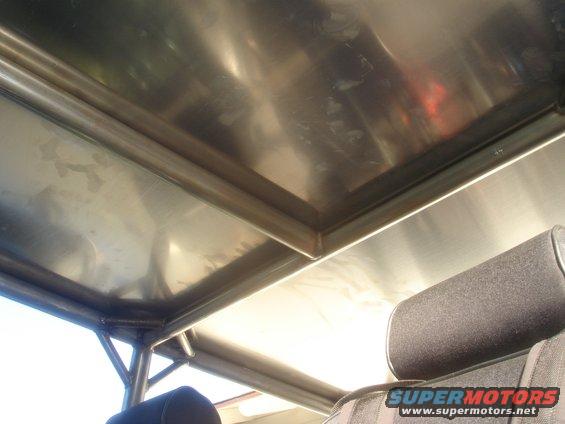 Interior view of a vehicle's metal roof and roll cage with a headrest visible