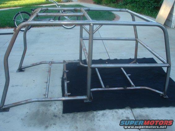 Roll cage frame on black tarp, bicycle in background