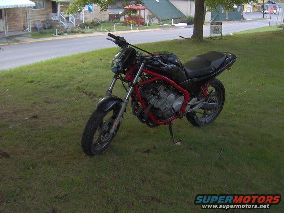 Black motorcycle with red frame parked on grass