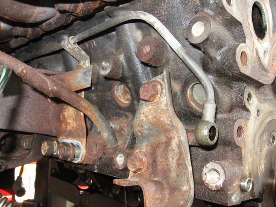Close-up of a rusty engine block with metal fuel lines attached