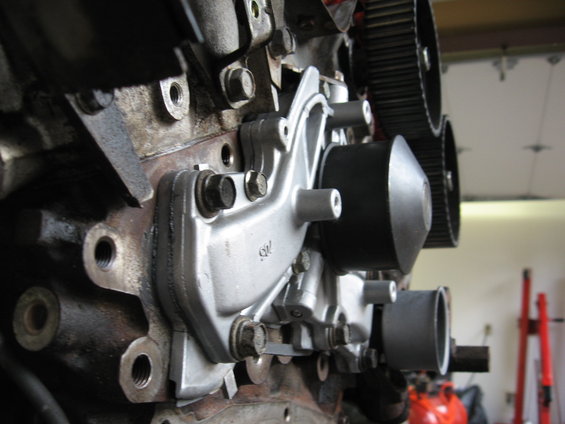 Close-up of an engine's water pump assembly with timing belts visible