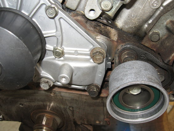 Engine component with a silver housing and a black pulley wheel