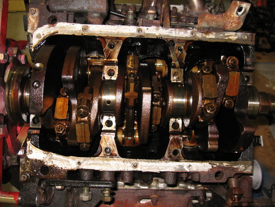 Engine block with crankshaft and connecting rods visible after oil pan removal