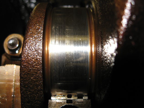 Close-up of a worn engine crankshaft bearing with copper and silver coloration