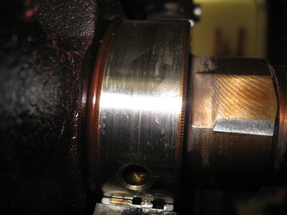 Close-up of a worn engine crankshaft bearing with oil residue