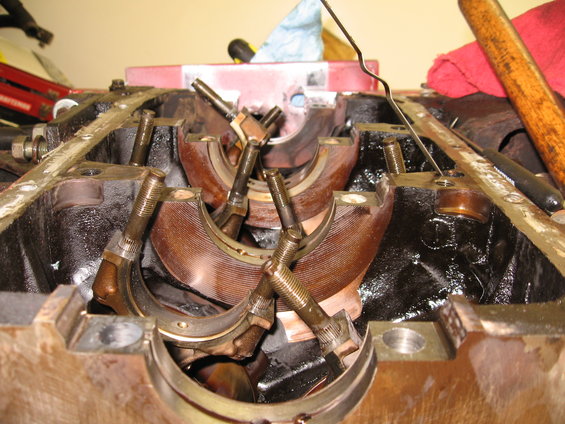 Engine block with crankshaft bearings and bolts, showing wear and oil