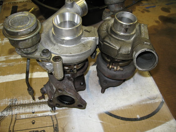 Two turbochargers, one with a wastegate actuator, resting on a surface