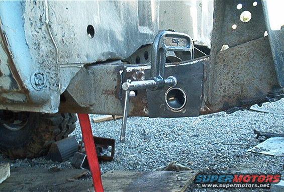 Rusty vehicle frame section with a C-clamp attached to a metal plate