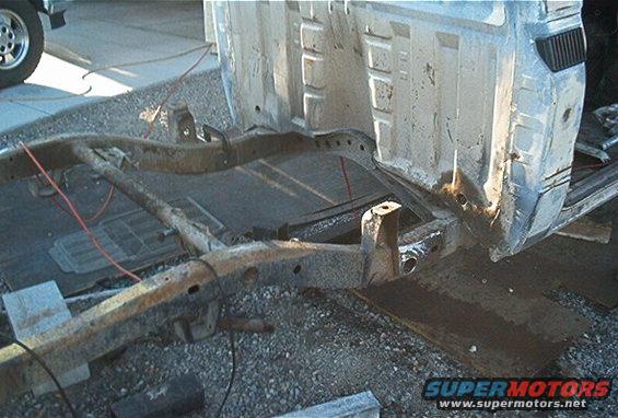 Rusty vehicle frame and rear body section with visible rust and damage
