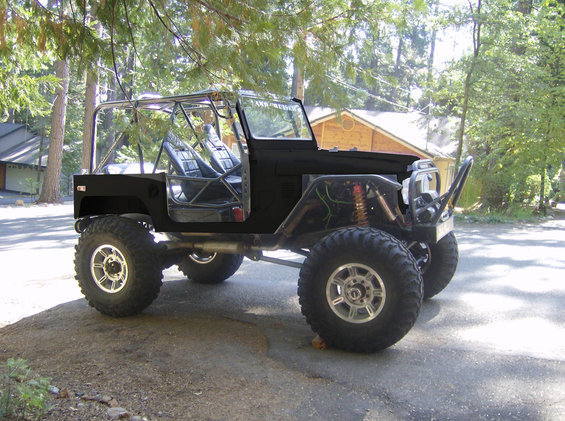 Black off-road vehicle with roll cage and large tires parked outdoors
