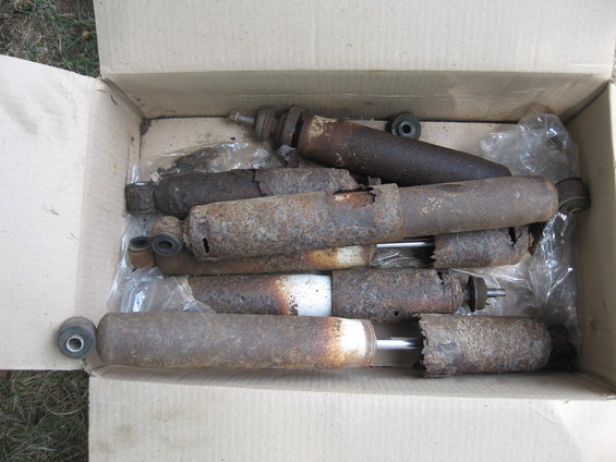 Several rusty shock absorbers in a cardboard box