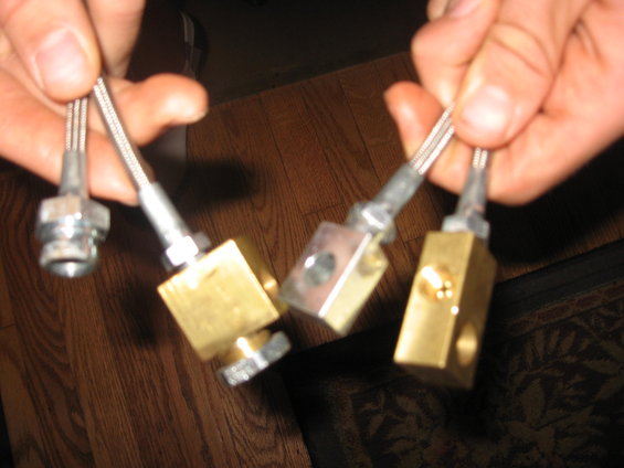 Four fuel injectors held by hands. Three have brass bodies, one has a metal body