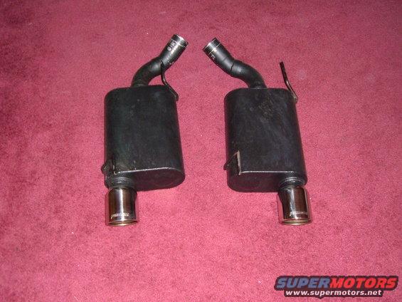 Pair of black mufflers with chrome tips, one with a bent pipe