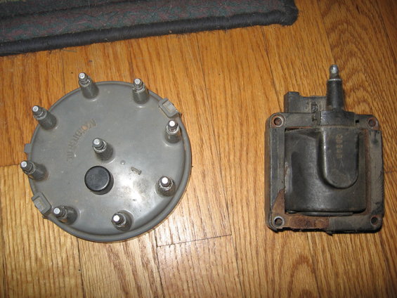 Distributor cap and ignition coil on wooden floor
