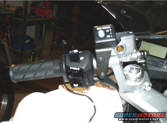 Close-up of motorcycle handlebar with grip, switches, and brake fluid reservoir