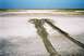 1990 Ford Bronco - Tire tracks mark a path across a dry, muddy plain under a bright blue sky.