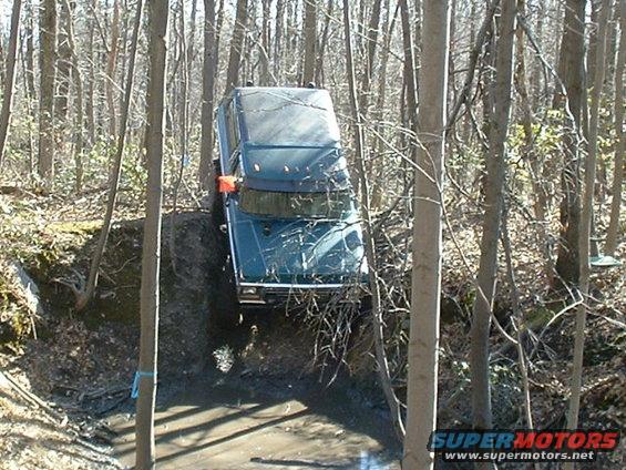 Jeep Wrangler driving through a muddy wooded area