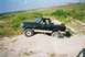 1990 Ford Bronco - This Ford Bronco is navigating a sandy, off-road terrain with one wheel partially buried.