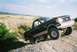 1990 Ford Bronco - This 1990 Ford Bronco navigates off-road terrain on a sandy incline under a bright sky.