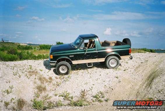 Green Ford F-Series truck with tan lower body trim parked on a dirt road