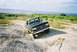 1990 Ford Bronco - This 1990 Ford Bronco is navigating a rough dirt path with a lake in the background.
