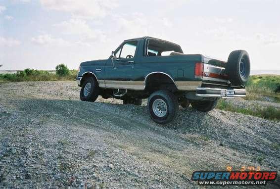 Dark green Ford Bronco parked on a gravel hill, spare tire mounted on the back