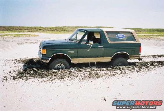 1990 Ford Bronco stuck in sand and mud, front wheels buried