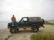 1990 Ford Bronco - Man sits on the hood of a 1990 Ford Bronco parked by the water.