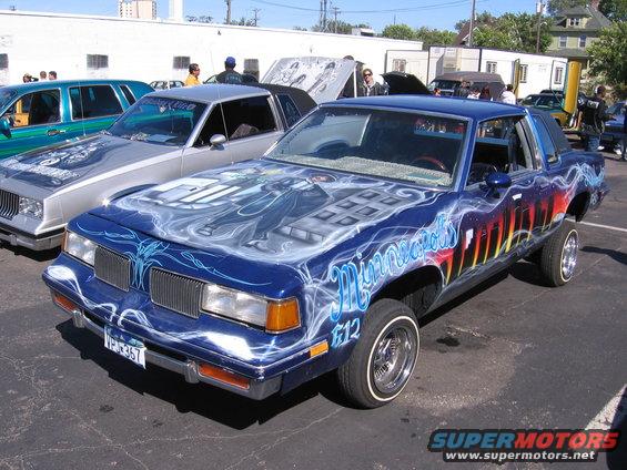 Blue coupe with airbrushed graphics on hood and sides, lowered stance